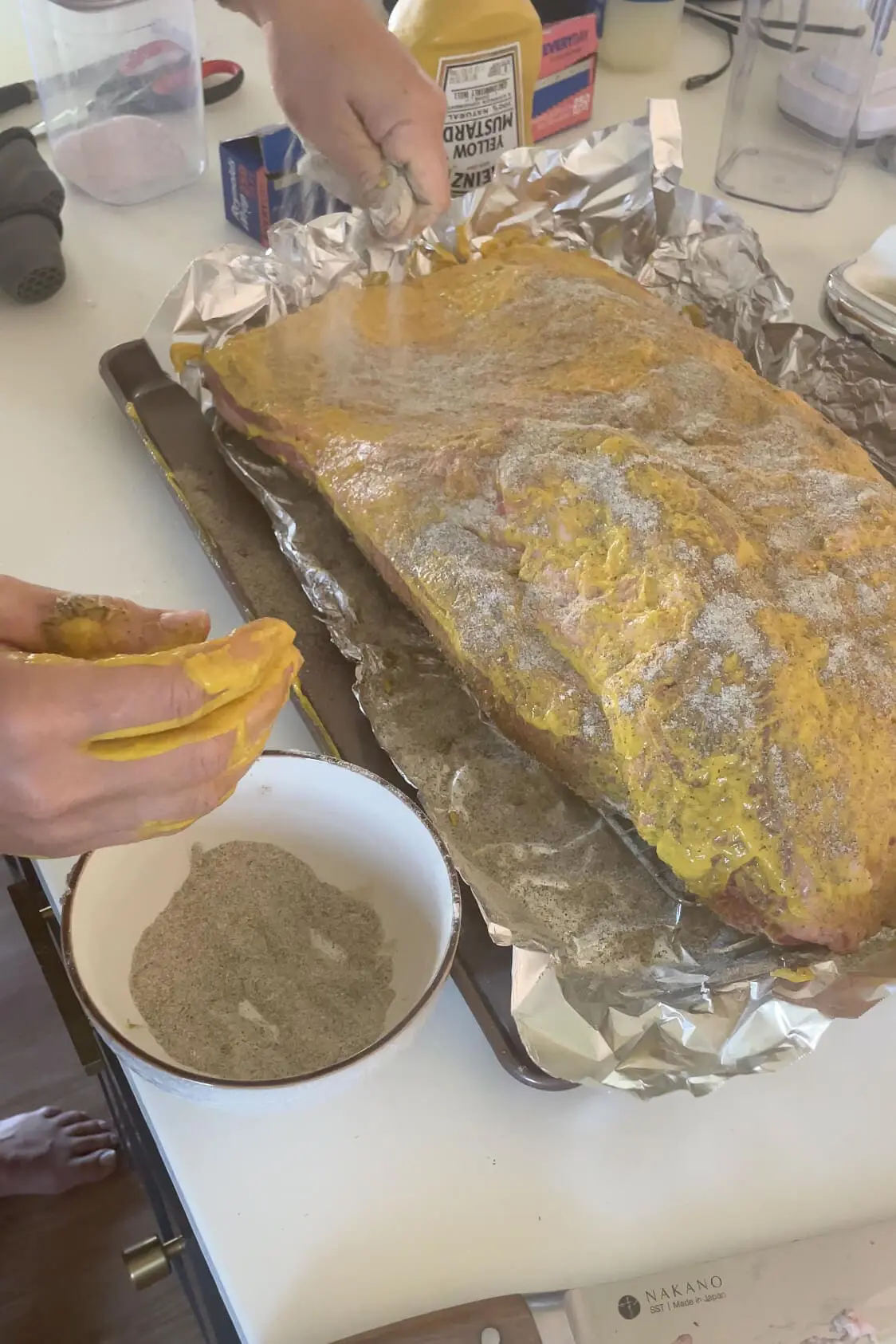 Covering a brisket with seasonings before putting it in the smoker. 